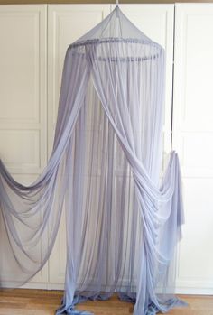 a canopy bed with sheer curtains hanging from it's sides, in a room