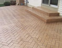 a brick patio in front of a house with steps leading up to the back door