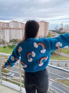 a woman standing on top of a balcony next to a railing looking out at the city