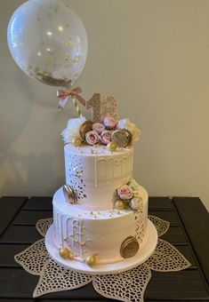 a white cake with flowers and balloons on top