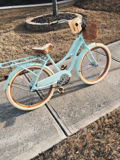 a blue bicycle parked on the sidewalk in front of a fire pit and some grass