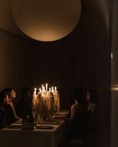 people sitting at a table with candles in the middle