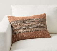 an orange and brown pillow sitting on top of a white couch