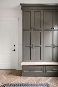 an empty room with gray cupboards and wooden flooring in the center, along with a rug on the floor