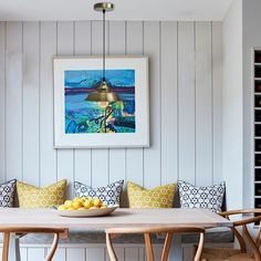 a dining room table with yellow and blue pillows on it, next to two chairs