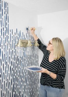 a woman is painting a wall with blue and white paint