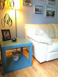 a white couch sitting next to a blue table on top of a hard wood floor