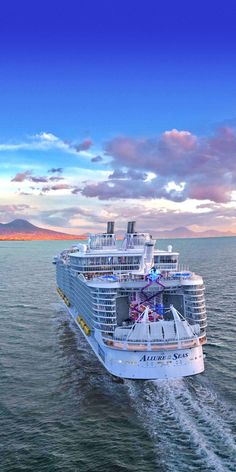 a large cruise ship sailing across the ocean under a blue sky with clouds in the background