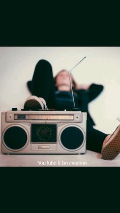 a man laying on the floor next to an old fashioned radio with his head resting on top of it