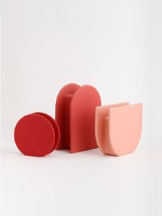 three pieces of red and pink soap on a white surface with one piece missing from the other