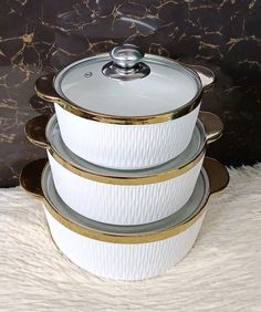 three white dishes stacked on top of each other in front of a black wall with gold trim