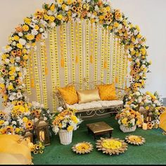 a decorated stage with sunflowers and other flowers on the side, surrounded by yellow pillows