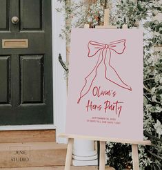 a pink sign with a bow on it sitting in front of a door next to a tree