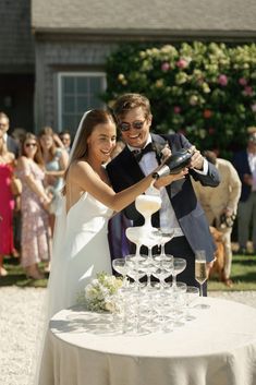 a newly married couple cutting their wedding cake with champagne glasses in front of the bride and groom