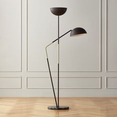 a floor lamp with two black lamps on it and a white wall in the background