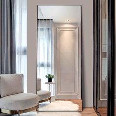 a large mirror sitting on top of a wooden floor next to a chair and window