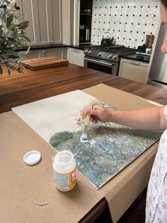 a woman is painting on a canvas in the kitchen