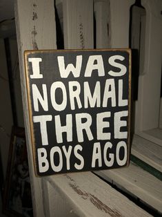 a wooden sign that says i was normal three boys ago on the side of a bench