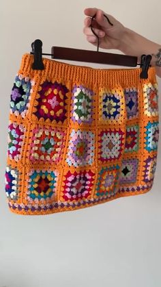 a person holding up a crocheted purse