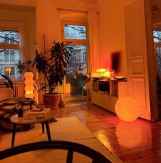 a living room filled with lots of furniture next to two large windows covered in red light