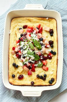 a casserole dish with fruit and cheese on top, sitting on a blue towel