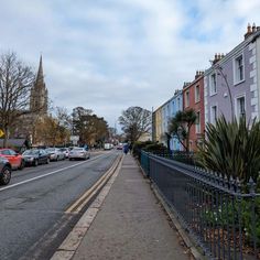 cars are parked on the side of the road in front of some buildings and trees