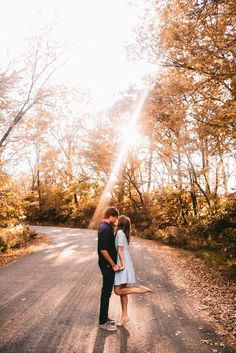 a man and woman standing on the side of a road in front of some trees