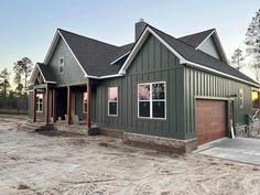 a house that is in the middle of some dirt and has two garages on each side