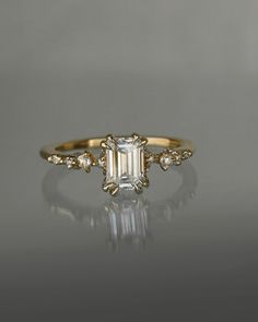 an emerald cut diamond engagement ring on a reflective surface