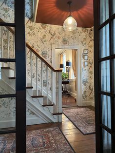 an entry way with floral wallpaper and rugs on the floor next to stairs