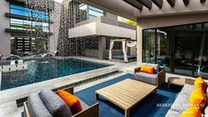 an outdoor living area with couches, tables and water feature in the pool that's surrounded by glass doors