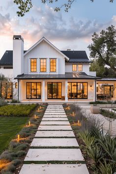 a large white house with lots of windows and lights on the walkway leading to it