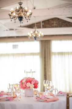 the table is set with pink flowers and wine glasses