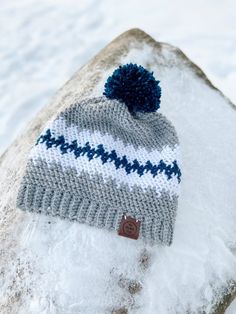 a knitted hat sitting on top of a snow covered rock in the middle of winter