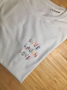 broderie arc-en-ciel faite à la main sur un t-shirt 100% coton biologique. Le vêtement peut être personnalisé GRATUITEMENT avec votre propre écriture ou dessin. Les chemises sont faites par un couple de gars. Chaque pièce est unique grâce à toutes les modifications qui peuvent y être apportées. Idéal pour un cadeau unique et spécial. Les photos sont des exemples de notre travail, suivez-nous sur instagram @paracosmbtd pour plus de photos de nos produits ! Les vêtements sont en coton biologique, Live Laugh Love, Diy And Crafts, Gender Neutral, Adult Outfits, Tops & Tees, T-shirt, Top Outfits, Couture, T Shirts