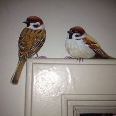 two birds sitting on top of a white door