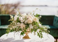 a vase filled with white flowers sitting on top of a table next to a green couch