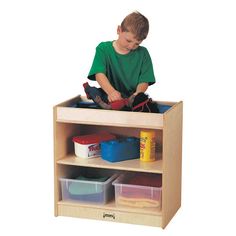 a young boy playing with toys in a wooden toy storage unit