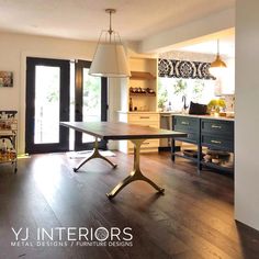 an open kitchen and dining room with wood floors, black cabinets and white lamps hanging from the ceiling