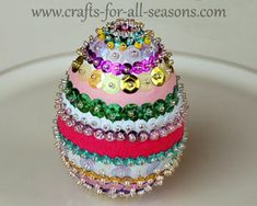 a stack of multicolored bracelets sitting on top of a white plate covered in lots of beads