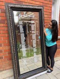 a woman standing next to a large framed sign