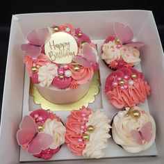 a birthday cake in a box with cupcakes and flowers on the top,