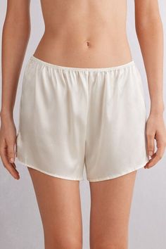 Shorts in light stretch silk satin with small side slits. Ideal to wear as a refined pair of shorts for night or as elegant loungewear. White Satin Bottoms For Summer, Satin Bottoms For Loungewear, Satin Shorts For Loungewear, Satin Short Bottoms For Loungewear, Satin Loungewear Bottoms Short Length, Satin Loungewear Shorts, Satin Lounge Shorts, Cream Silk Bottoms For Summer, Summer Silk Cream Bottoms