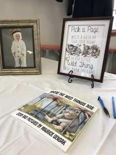 two framed pictures are on a table with pens and pencils in front of them