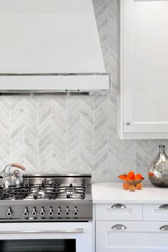 a stove top oven sitting inside of a kitchen next to white cabinets and counter tops