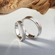 two wedding rings sitting on top of a piece of driftwood next to each other