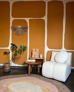 a living room with an orange wall and white chair next to a potted plant