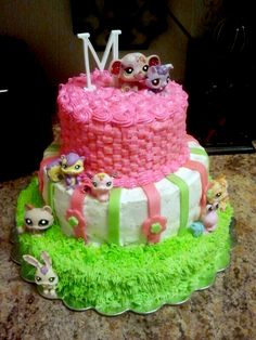 a three tiered cake decorated with pink and green icing, featuring littlest pets