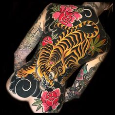 a man with tattoos on his back has a tiger and flowers tattoo on his body