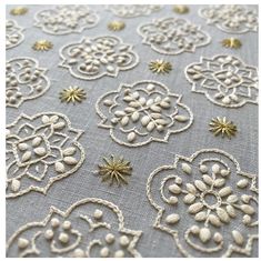 an embroidered fabric with gold and white flowers on grey background, showing the details of lacework